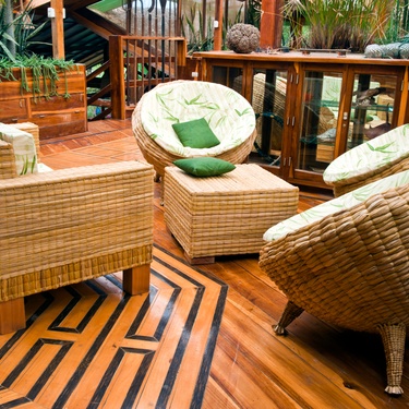 An interior living space of a home with a bamboo furniture set, including a sofa, ottoman, and three chairs.