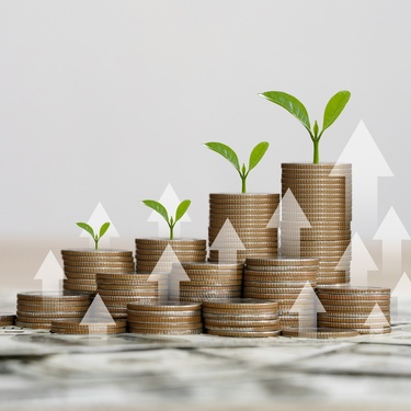 There are several stacks of coins, and each stack has a green plant growing out the top of it.
