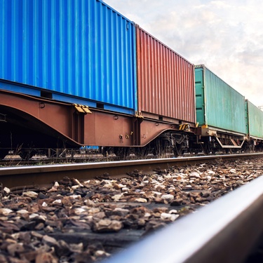 A close-up of a railway with train wagons loaded with multicolored cargo containers for shipping companies.