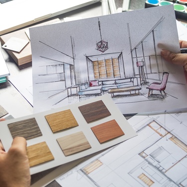 A close-up of an interior designer's work that includes hand sketches, design plans, blueprints, and material selections.