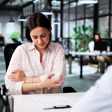 An injured woman and a lawyer discuss disability compensation in the lawyer's office as she points out her injuries.