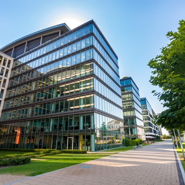 A large commercial property features beautifully groomed landscaping, clean glass windows, and a brick sidewalk.