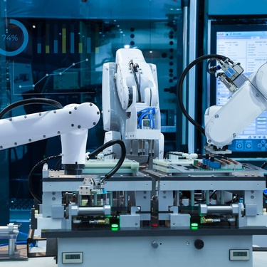 A factory with an automated robotic system handling the production line. Robot arms are putting together circuit boards.