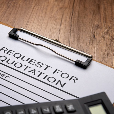 A black calculator rests on a clipboard holding a white sheet labeled 'Request for Quotation' with printed lines.