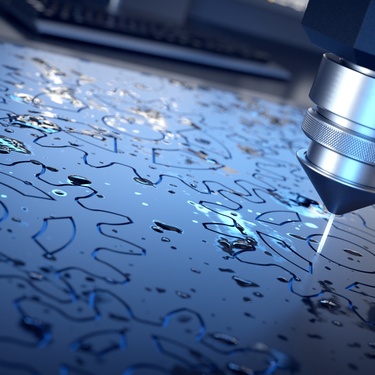 A waterjet cutting through a sheet of metal to create multiple gears. The cutter appears to be finishing up with this sheet.