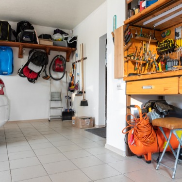 A car is backed up into a garage, and there is a workbench on the opposite side of the garage.