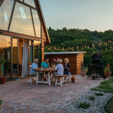 A beautiful evening in the backyard of a home with a family gathered around the table under the patio lights.